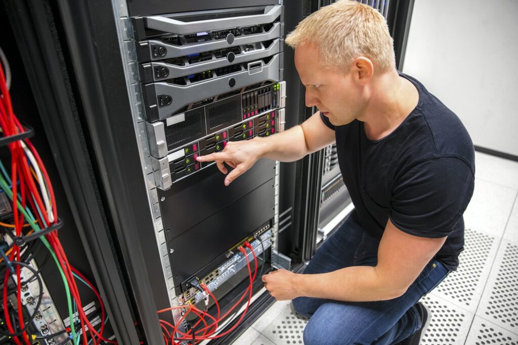 IT Technician Monitors Server On Rack In Datacenter