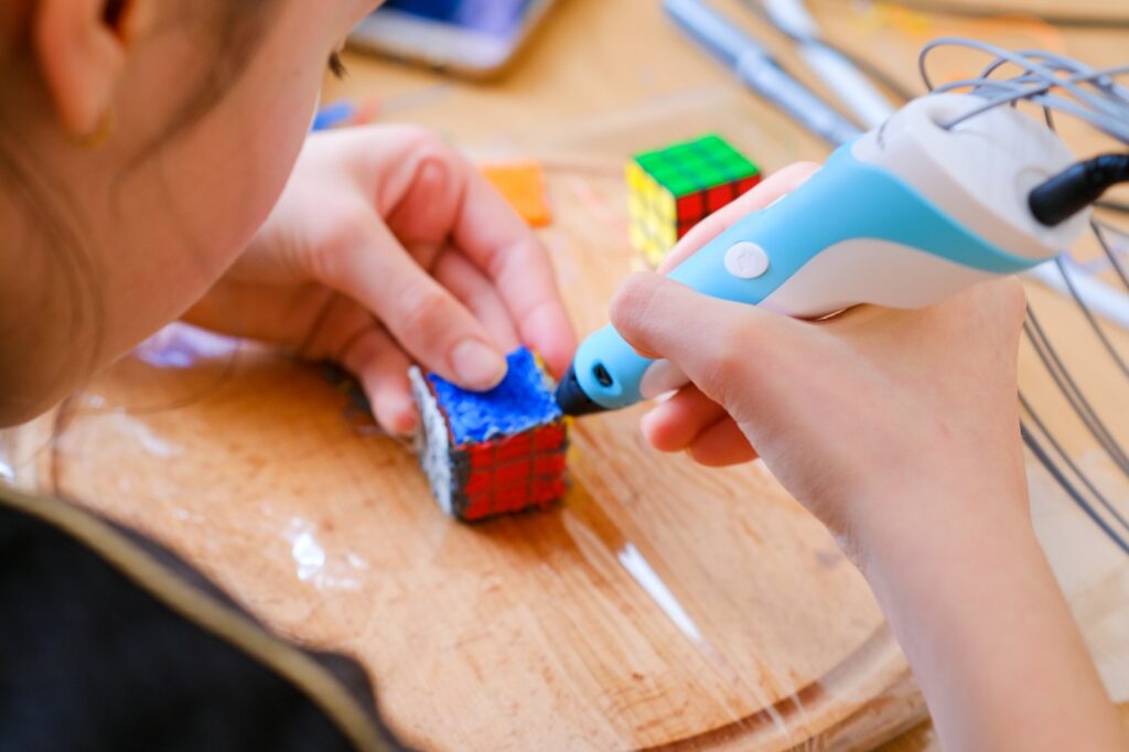 The girl makes a toy Rubik's cube with a 3D pen. Crafting. Creativity. Simple pops of color.